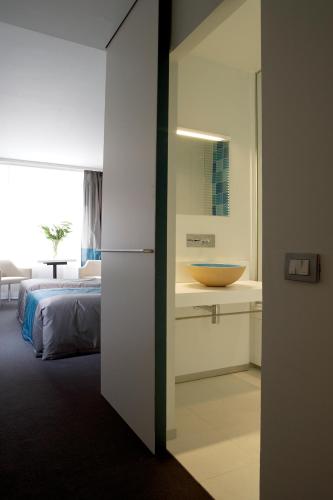 a bathroom with a sink and a bed in a room at Parkhotel Roeselare in Roeselare