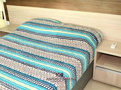 Una cama con una manta de colores encima. en 1041 - Apartamento na Praia de Bombinhas para locação - Residencial Egídio Pinheiro 304 B, en Bombinhas