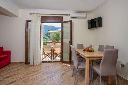 una sala da pranzo con tavolo, sedie e porta scorrevole in vetro di Kavadias Apartments a Vassiliki