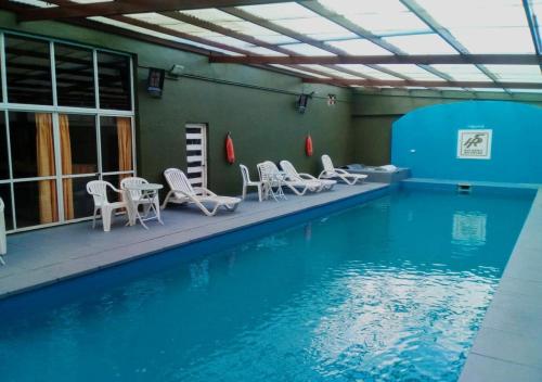 una piscina con sillas y mesas blancas y una piscina en Hotel San Remo Majestic, en Mar de Ajó