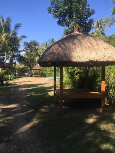a hut with a bench under a grass umbrella at Red island villas in Banyuwangi