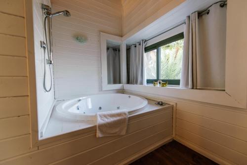 baño con bañera y ventana en Somewhere - Chalets in the Arava, en Ẕofar