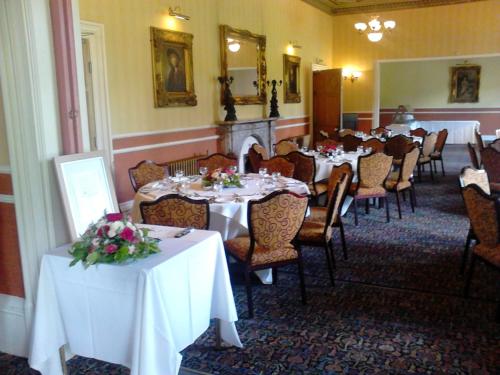 a dining room with tables and chairs with flowers on them at The Ennerdale Country House Hotel ‘A Bespoke Hotel’ in Cleator