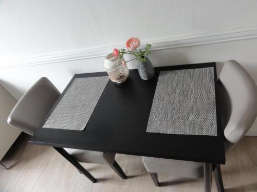 une table noire avec deux chaises et deux vases dans l'établissement Pension Corper, à Zandvoort