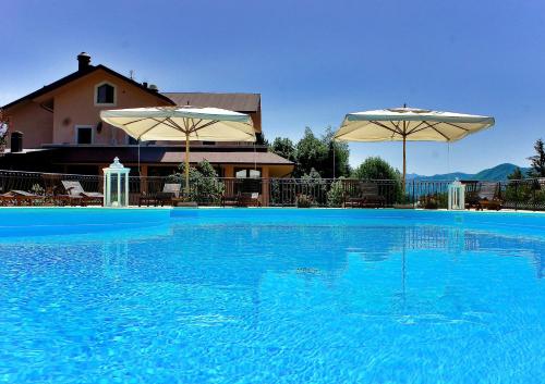 a large blue swimming pool with two umbrellas at Bucaneve in Pescasseroli