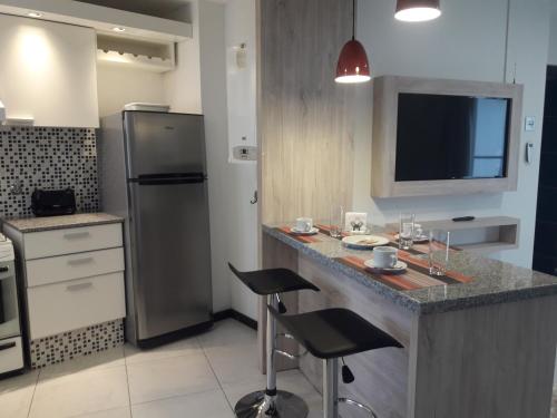 a kitchen with a counter with stools and a refrigerator at Departamento Torre Sofitel in Río Cuarto