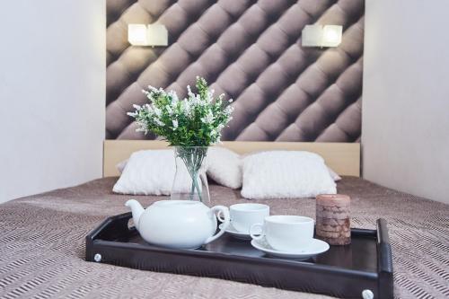 a tray with two cups and a vase with flowers on a bed at Langery Residence Central Apartments in Odesa