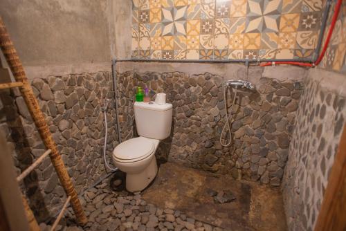 a small bathroom with a toilet and a shower at The Village Bed and Breakfast in Lovina