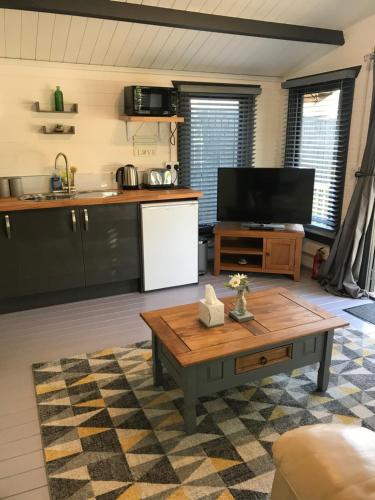 a living room with a table and a kitchen at Star Cabin Lairg in Lairg