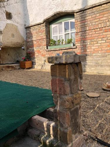 a brick house with a window with plants in it at Kakukkfu Barlang-Vendeghaz in Noszvaj