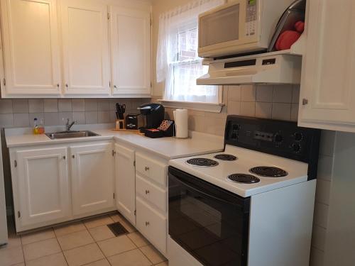 a white kitchen with a stove and a sink at Sarnia's Man Cave welcomes you... Game ON! in Sarnia
