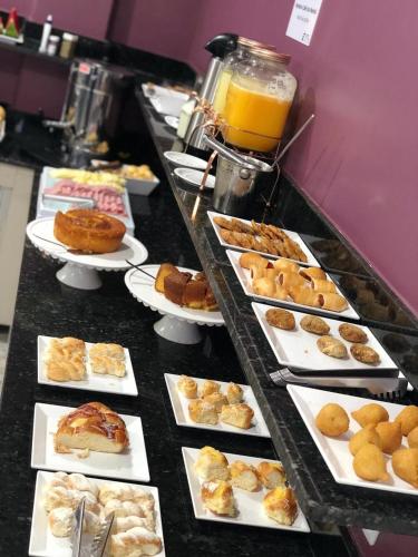 a buffet line with plates of pastries and orange juice at Hotel Elite in Rio Verde