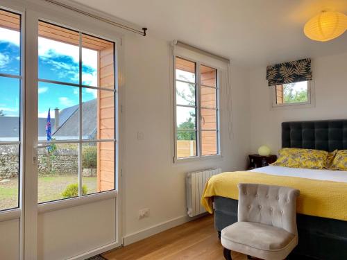 a bedroom with a bed and a chair and windows at Villa kahlo Omaha Beach in Colleville-sur-Mer