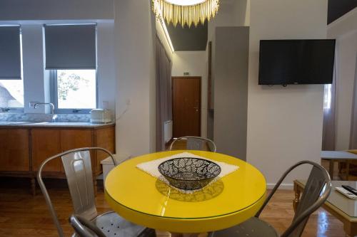 a yellow dining room table with chairs and a television at ATHENIAN YARD SUITES in Athens