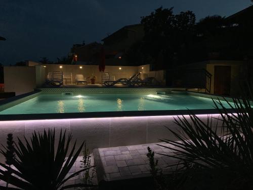 a swimming pool at night with lights in a house at Grand Pool Apartment Ika-Opatija in Opatija