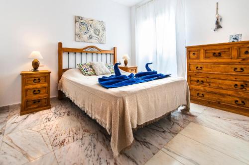 a bedroom with a bed with blue sheets and a dresser at Apartamento Ocean Vista in El Cotillo