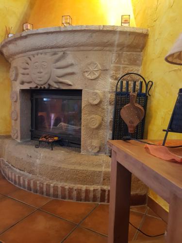 a stone fireplace in a living room with a table at Posada La Fabula in Santillana del Mar