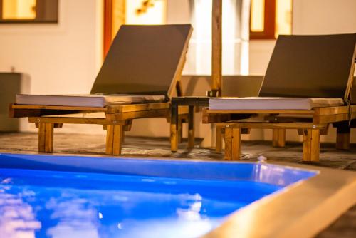 - deux chaises assises à côté de la piscine dans l'établissement Rhenea Resort, à Imerovigli