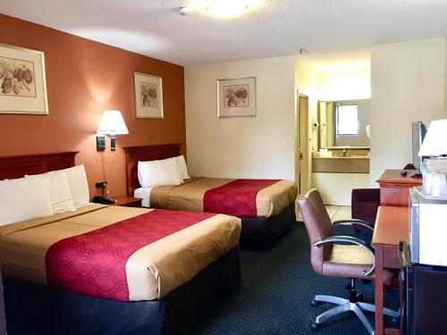 a hotel room with two beds and a desk at Red Carpet Inn Norwalk in Norwalk