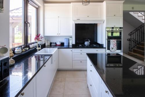 a kitchen with white cabinets and black counter tops at Willa Liski in Stare Juchy