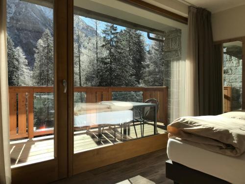 a room with a balcony with a bed and a glass door at Hotel Le Cime in Val Masino