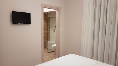 a bathroom with a toilet and a television on a wall at Vito's Parga View Apartments in Parga