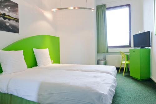 a bedroom with a large bed with a green headboard at Hotel Siru in Brussels