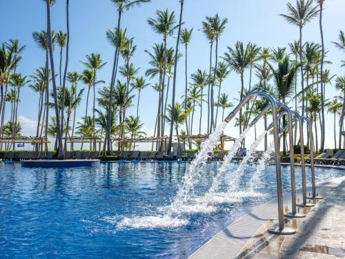 a fountain in a swimming pool with palm trees at Barceló Bávaro Beach - Adults Only All Inclusive in Punta Cana