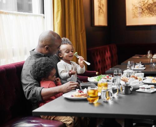 a man and two children sitting at a table in a restaurant at Four Seasons Hotel New York Downtown in New York