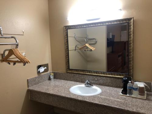 La salle de bains est pourvue d'un lavabo et d'un miroir. dans l'établissement Orange Tustin Inn in Orange, à Orange