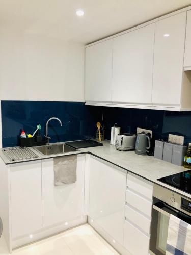 a kitchen with white cabinets and a sink at Oxford Studios in Kidlington