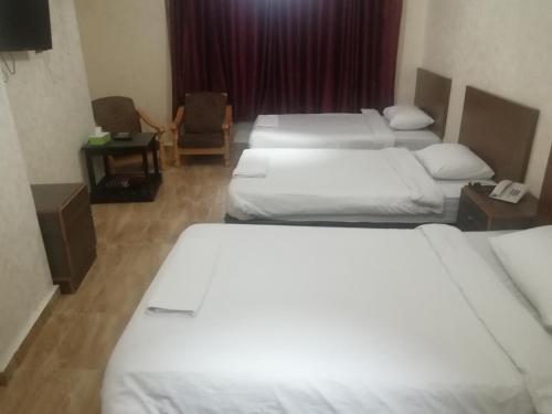 Cette chambre d'hôtel comprend 4 lits avec des draps blancs. dans l'établissement Al-Houriat Hotel, à Amman
