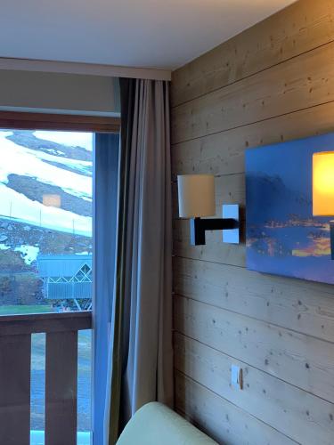 a bedroom with a wooden wall with a window at Val Thorens Temple of the Sun - ski in, ski out in Val Thorens