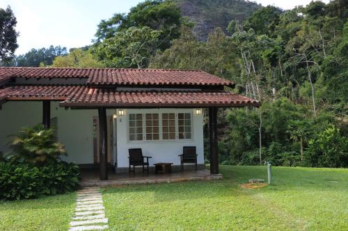 a small white house with two chairs in a yard at Auberge Suisse Pousada in Nova Friburgo