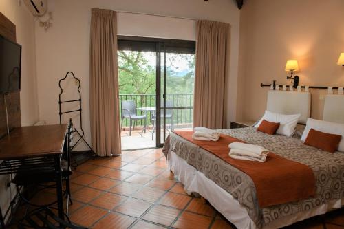 1 dormitorio con cama, mesa y balcón en Hotel Selva Montana en San Lorenzo