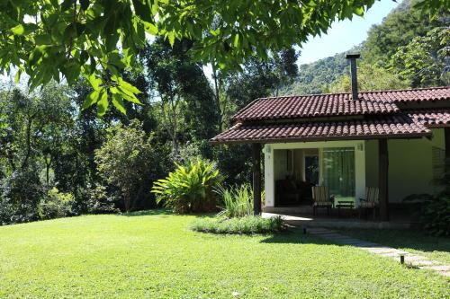 a house with a porch and a grass yard at Auberge Suisse Pousada in Nova Friburgo