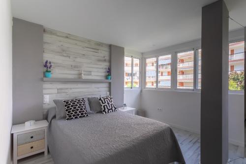 ein Schlafzimmer mit einem Bett und zwei Fenstern in der Unterkunft Apartamento Deluxe a 50m de Playa - Aire Wifi Parking in Gandía