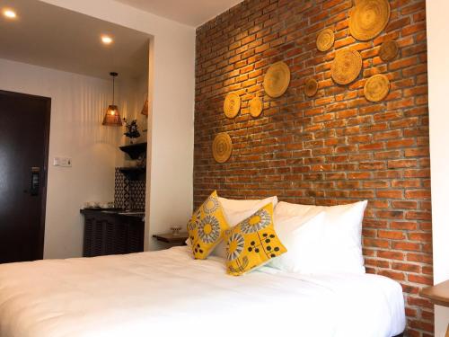 a bedroom with a brick wall and a bed with pillows at Banana Flower Homestay in Da Nang