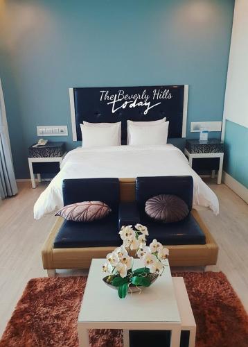 a bedroom with a large bed and a table with flowers at The Beverly Hills Hotel in Nakhon Ratchasima