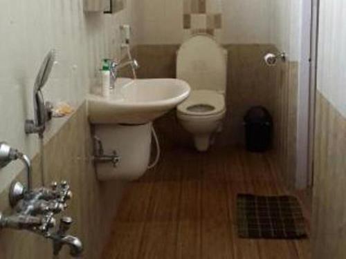 a bathroom with a white sink and a toilet at Vamoose Madhumita Homestay in Guwahati