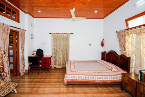 a bedroom with a bed and a desk in it at Vamoose Madhumita Homestay in Guwahati