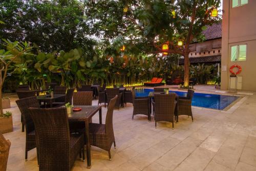 un restaurant avec des tables et des chaises ainsi qu'une piscine dans l'établissement Sunwood Hotel Arianz Mataram, à Mataram