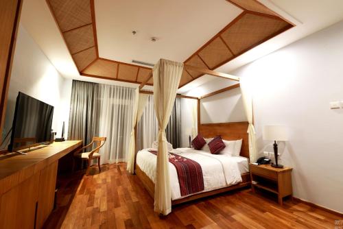 a bedroom with a canopy bed and a television at NDC Resort & Spa in Manado