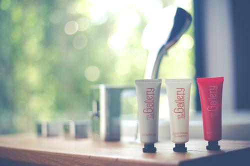 three tubes of sunscreen sitting on a wooden table at The Gallery Hotel Nai Harn in Nai Harn Beach