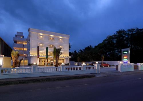 a white building with a fence in front of a street at Hotel Park Residency Thrissur in Trichūr