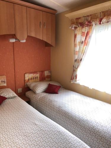 two beds in a small bedroom with a window at 40 Glenfinart Caravan Park in Dunoon