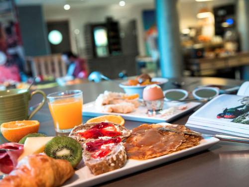 a table with two plates of food and orange juice at ibis Styles Vierzon in Vierzon