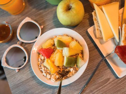 a bowl of cereal with fruit and an apple on a table at ibis Styles Vierzon in Vierzon