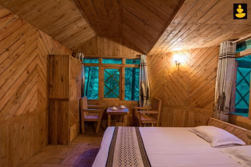 a bedroom with a bed in a wooden room at LivingStone Ojuven Treehouses in Shimla