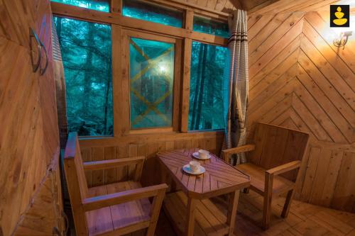 a wooden room with a table and chairs in a cabin at LivingStone Ojuven Treehouses in Shimla